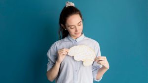 Mujer sosteniendo un cerebro de papel a la altura del corazón
