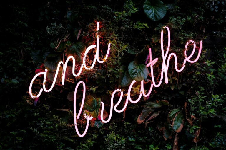 Letras en Neón sobre un fondo vegetal que dice: Just Breathe