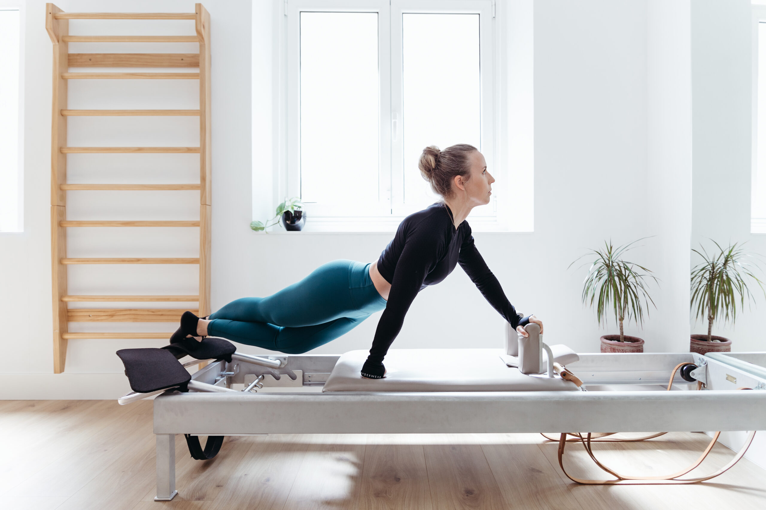 Profesora de pilates entrenando en una máquina restform, en un espacio amplio, minimalista con luz natural